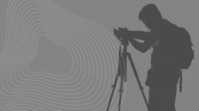 fundo cinza, desenhos geométricos, e imagem sombreada de um fotógrafo com sua câmera.
