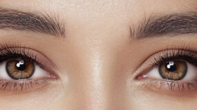 Dois olhos de uma mulher olhando para frente. A imagem foca em sua sobrancelha e cílios.